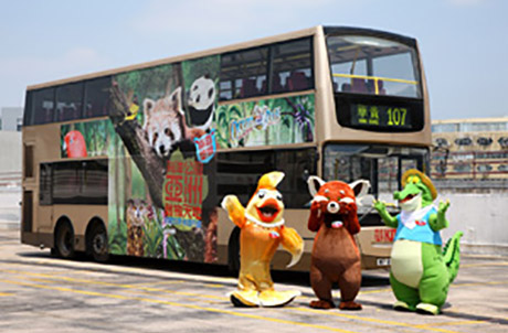 图一：40 辆走遍港九新界之九巴披上以「亚洲动物天地」为主题的新衣，前为海洋公园吉祥物（左起）「俏鱼姬」、「小红熊」及「大胃鳄」